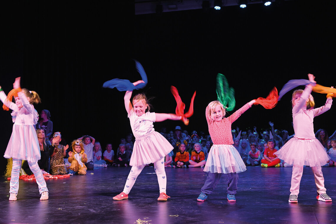 Vier Kinder tanzen mit Stoffbändern